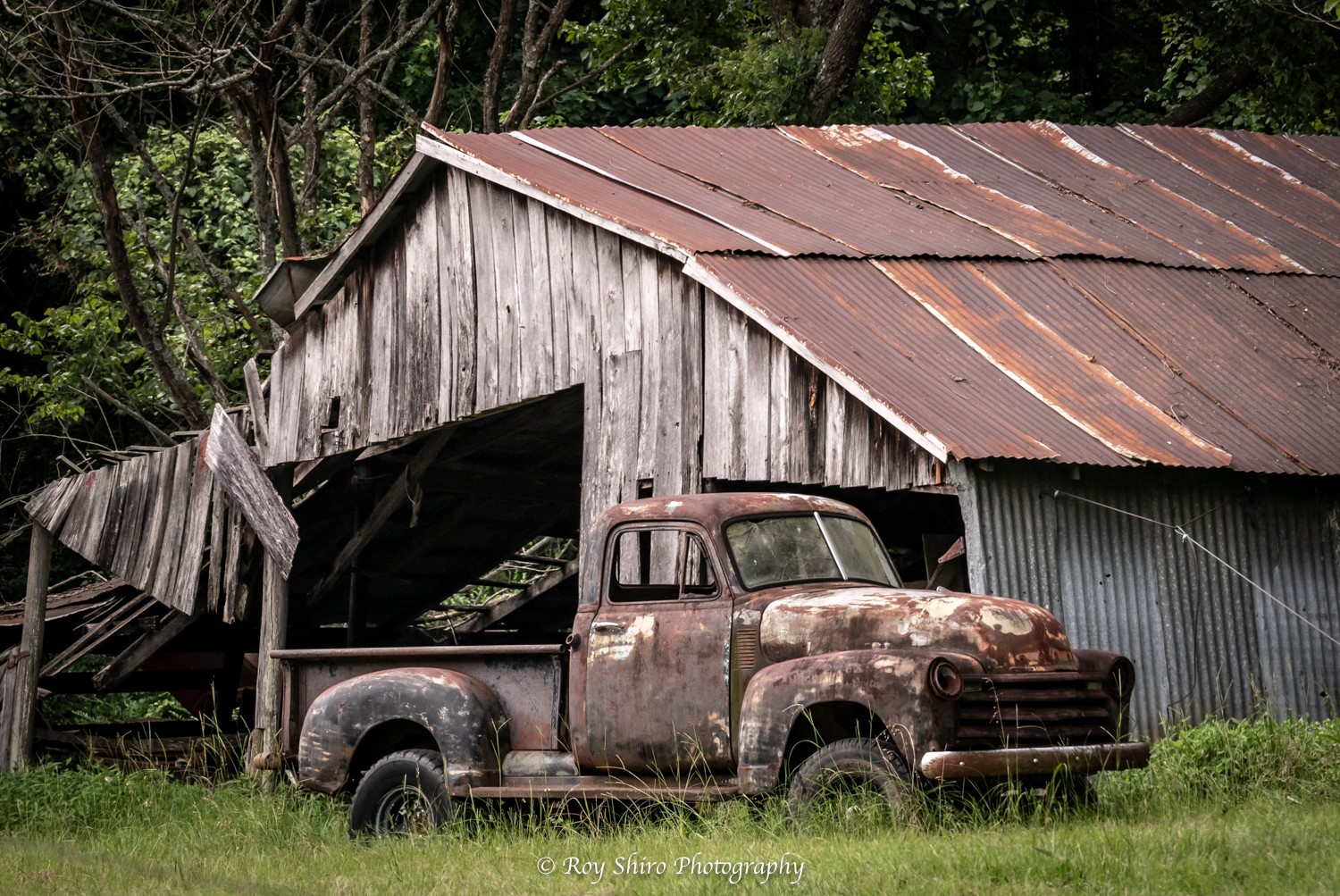 Rustic barn and rusty antique truck in a green pasture